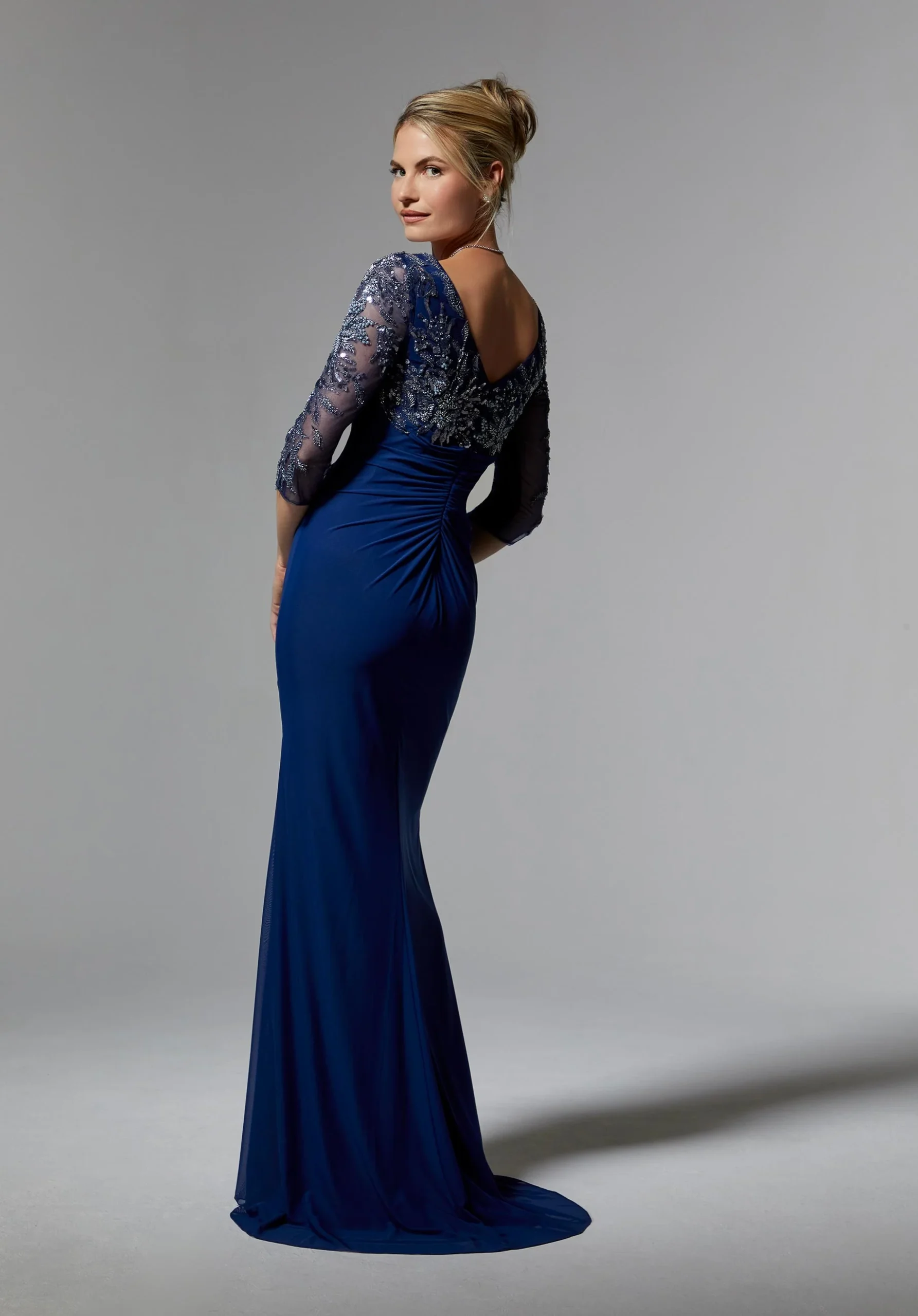 Woman in blue gown from back showing lace bodice and ruched detailing.