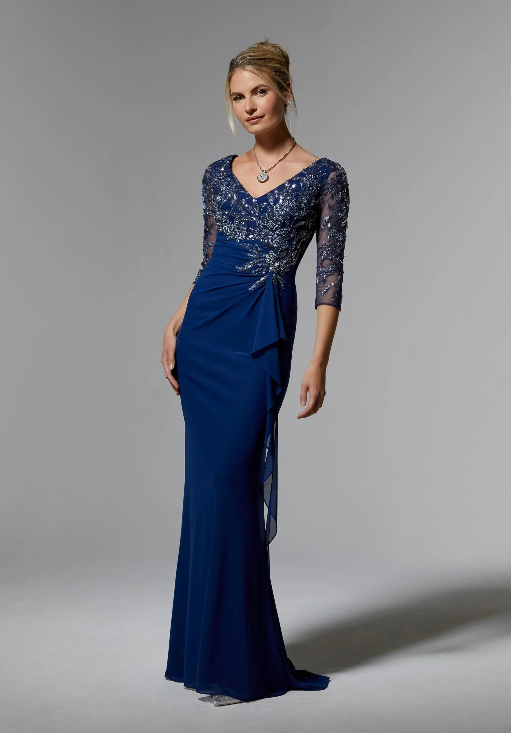 Woman in blue gown showing lace bodice and elegant draped skirt from side view.